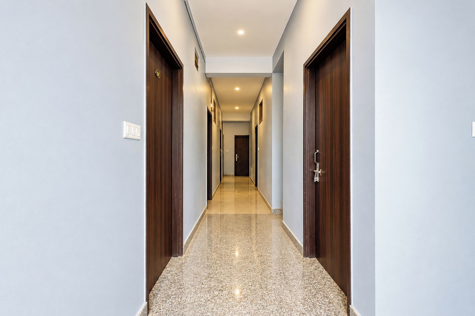 Un pasillo con puertas de madera y suelo de baldosas, que conduce a una habitación.