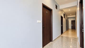 Passadís d'hotel amb diverses portes, un interruptor de llum i un paviment de rajola.