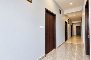 Ein Hotelgang mit mehreren Türen, einem Lichtschalter und einem gefliesten Boden.