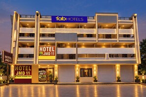 Un hotel de varios pisos con un cartel llamativo de 'fab hotels', múltiples balcones y una entrada grande con un toldo cerrado.