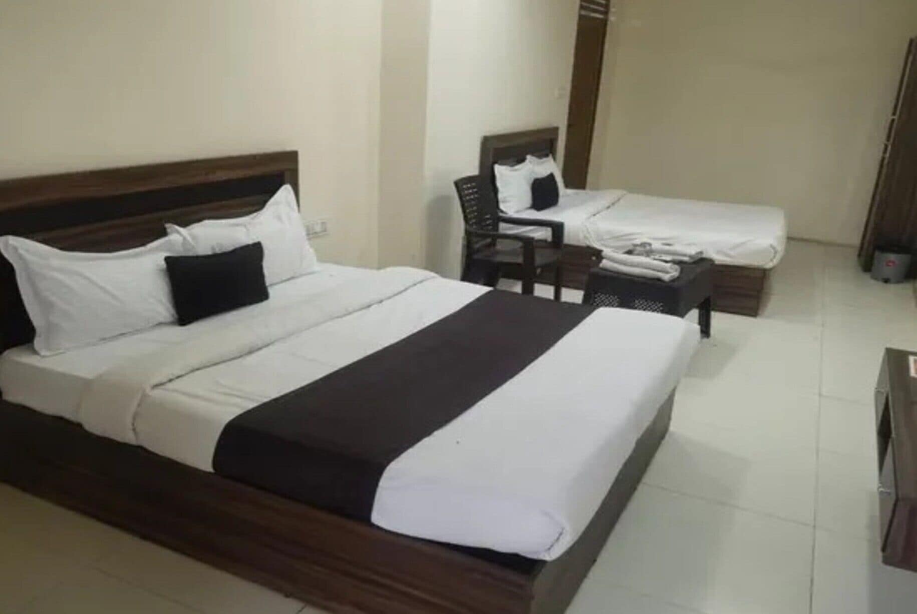 A hotel room with a large bed, a smaller bed, a chair, and a desk.