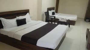 Una habitación de hotel con una cama grande, una cama más pequeña, una silla y un escritorio.