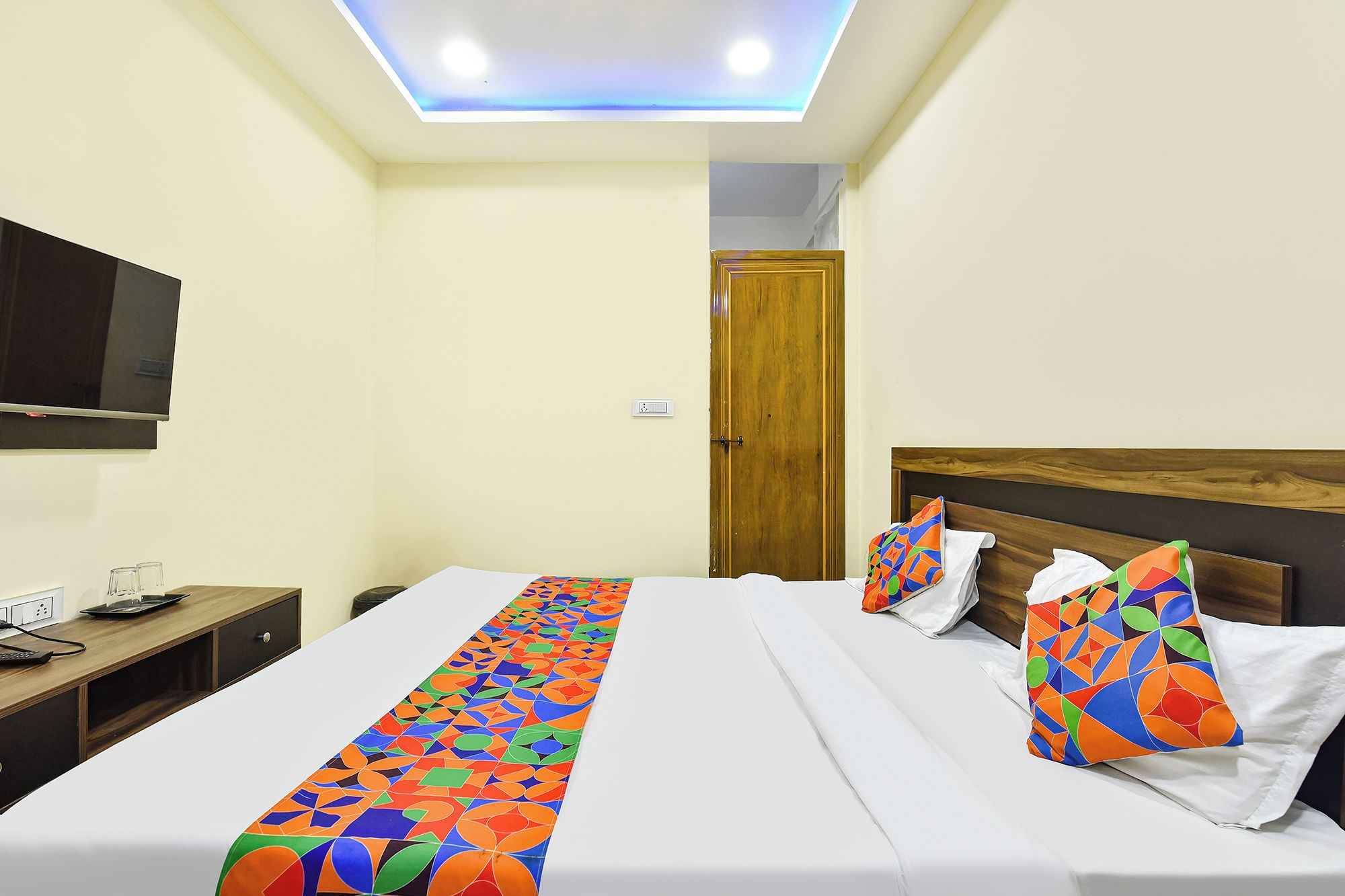 A hotel room with a bed, bedside table, and a television.