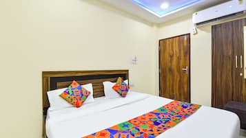 A hotel room with a bed, a wooden wardrobe, and a ceiling light.