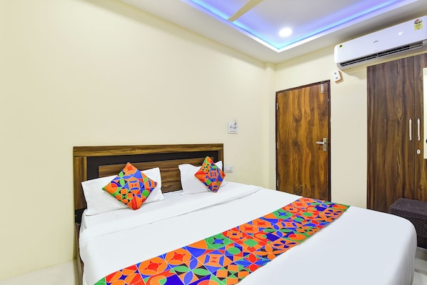 Una habitación de hotel con una cama, un armario de madera y una lámpara en el techo.