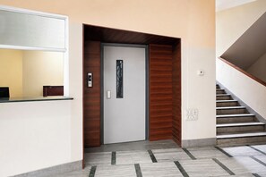 A modern interior with a wooden door, a reception desk, and a staircase.