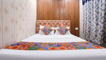 A bed with a geometric-patterned bedspread, a tufted headboard, and two decorative pillows.
