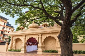 A traditional building with ornate arches and domes, surrounded by lush greenery and modern buildings. - Via Shiv Vandana Inn (Mumbai)