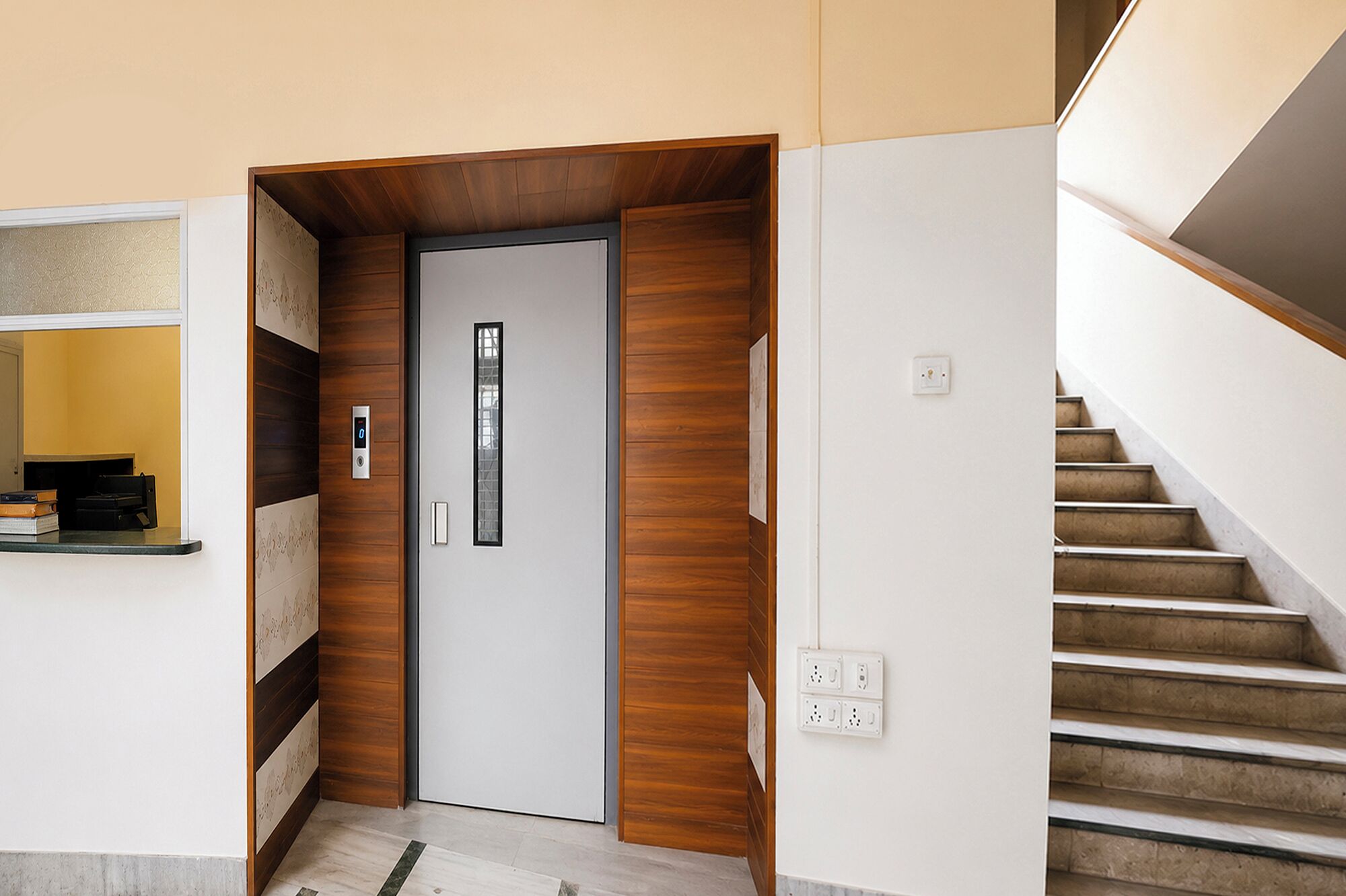 A modern interior with a wooden panel wall, a white door with a vertical window, and a staircase with beige steps.
