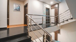 Un interior moderno con una escalera, un cuadro en la pared y una puerta que da a otra habitación.