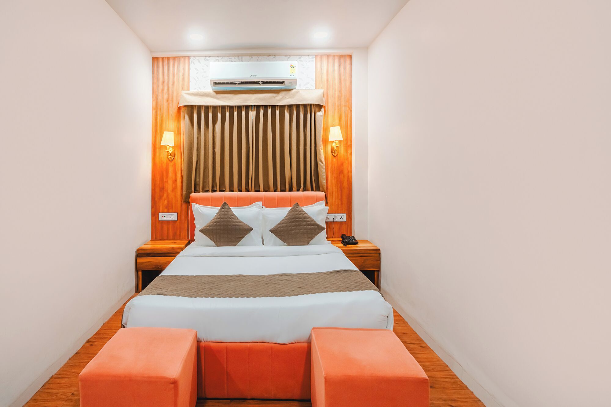 Ein Hotelzimmer mit einem Bett, Nachttischlampen, einer Klimaanlage und einem Telefon auf dem Nachttisch.