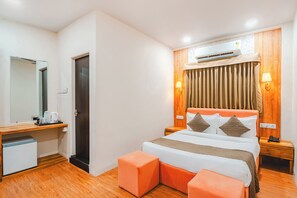 Ein Hotelzimmer mit einem Bett, einem Schreibtisch mit Spiegel, einer Kaffeemaschine, einer Klimaanlage und Holzboden.