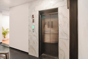 A modern elevator with a marble wall and a digital display. - FabHotel Asilo Prime (Indore)
