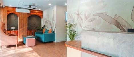A reception area with a wooden reception desk, a blue sofa, and a globe on a wooden cabinet.