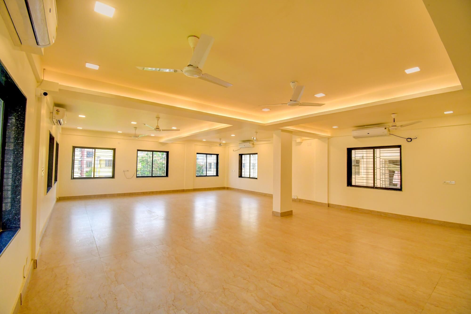 A spacious room with multiple windows, ceiling fans, and recessed lighting.