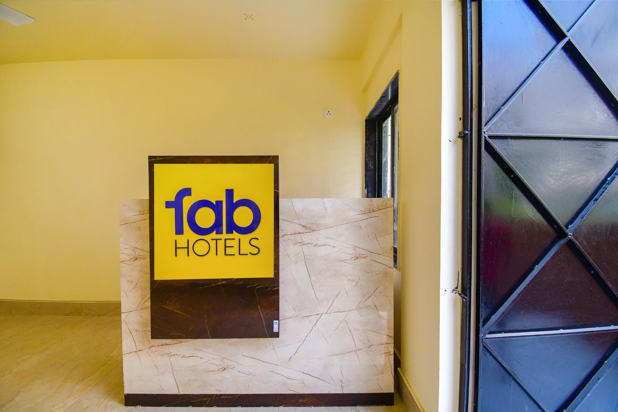 Ein Empfangstresen mit einem Schild für 'fab hotels' an einer gelben Wand.
