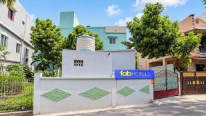 Una propiedad cercada con un letrero de 'fabHOTELS' y un tanque de agua en el techo.
