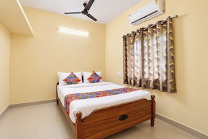 Une chambre à coucher avec un lit, un ventilateur de plafond, un climatiseur et une fenêtre avec des rideaux.