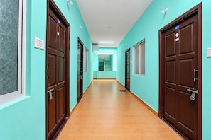 Un pasillo con paredes verde azulado, puertas de madera y piso de baldosas.