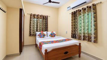 A hotel room with a bed, curtains, an air conditioning unit, and a ceiling fan.