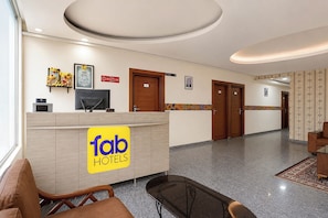 Ein Hotel-Empfangsbereich mit einer Rezeption, einer Sitzecke und einem Korridor zu den Zimmern.