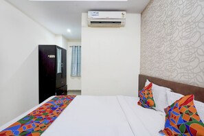Una habitación de hotel con cama, armario, equipo de aire acondicionado y pared con diseño.