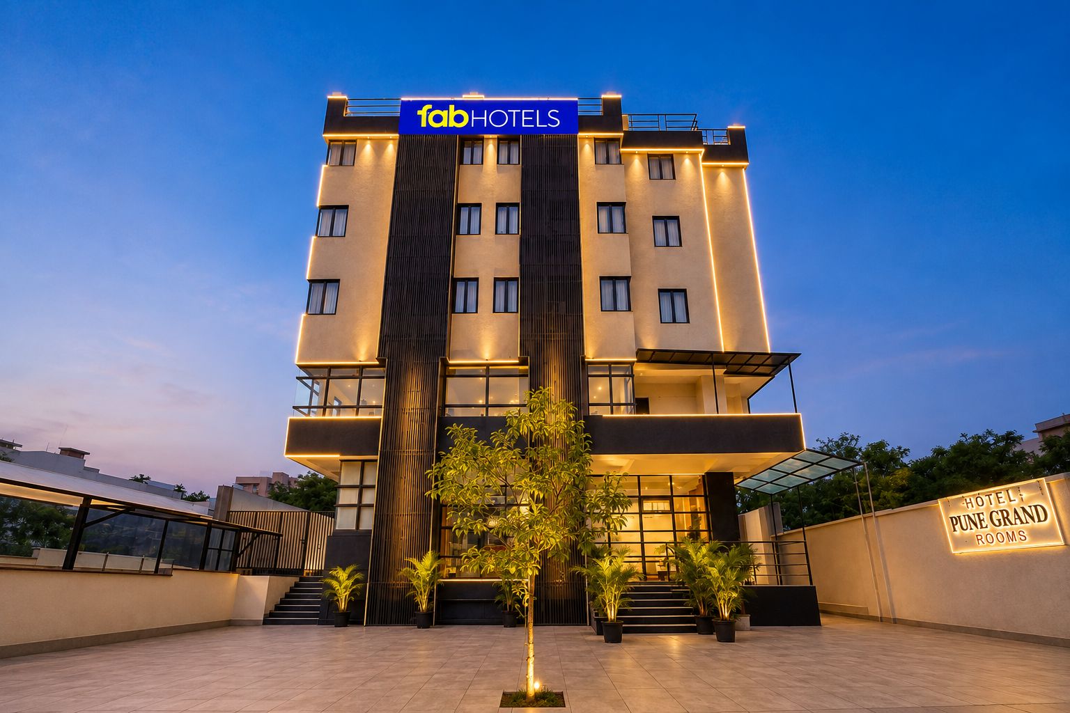 Een modern hotelgebouw met een bord waarop 'fabHOTELS' en 'HOTEL PUNE GRAND ROOMS' staat.