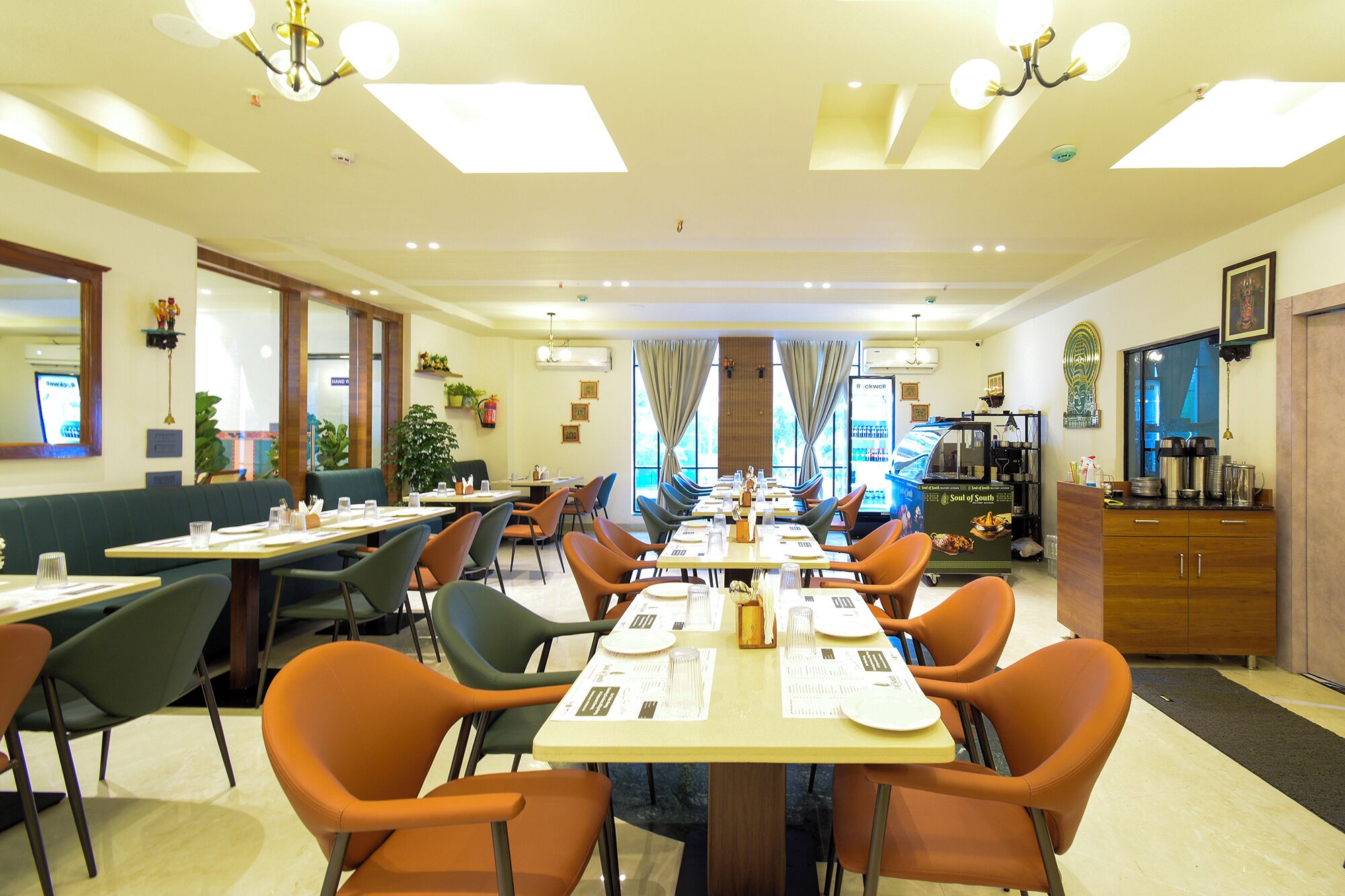 Un espace repas d’hôtel comprenant plusieurs tables et chaises, une machine à café et un réfrigérateur.