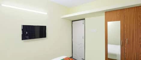 Un dormitorio con cama, ventilador de techo, televisor montado en la pared y armario de madera.