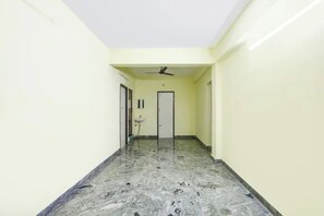 Un pasillo con ventilador de techo, una puerta y un lavamanos.