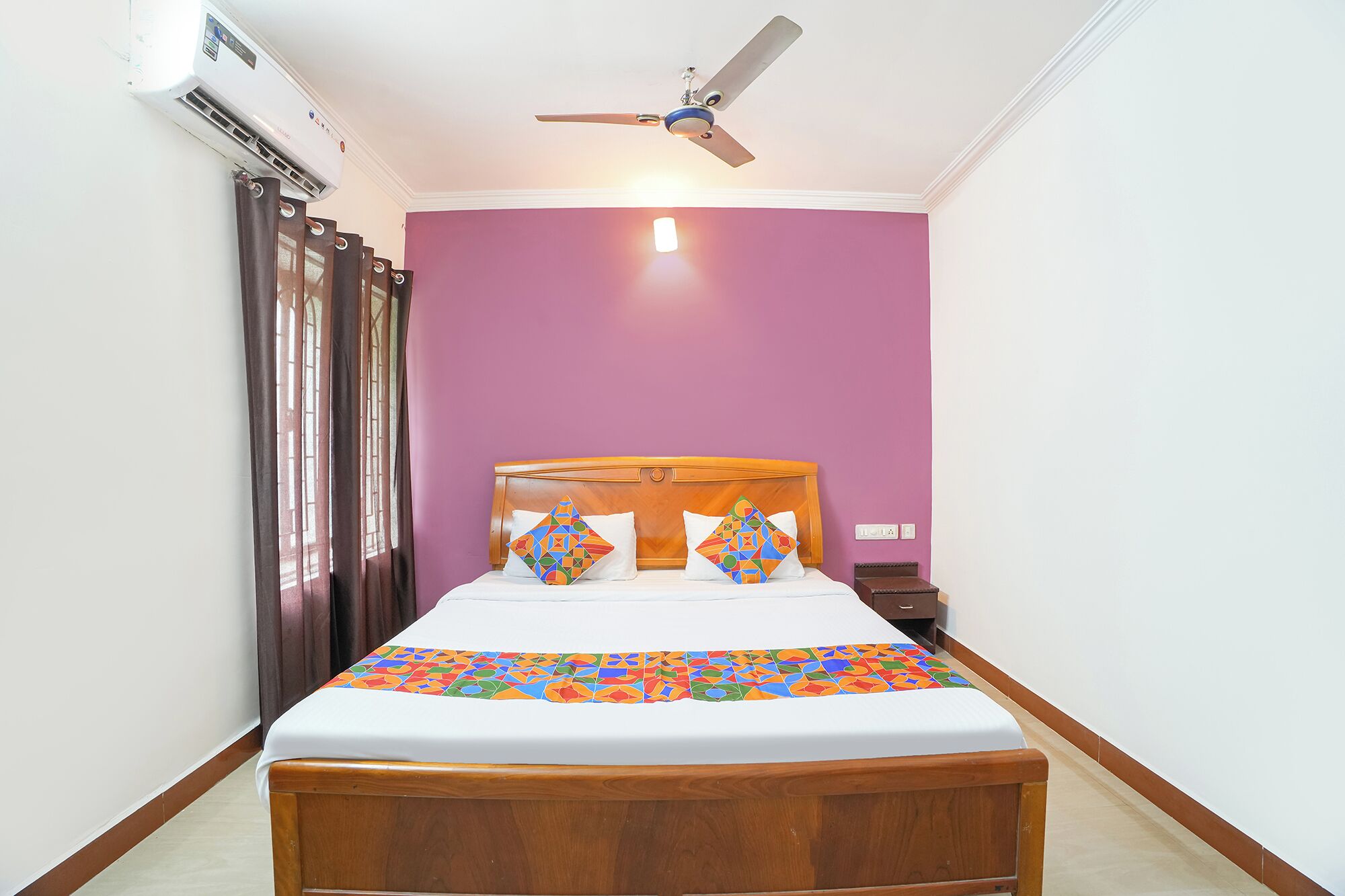 A bedroom with a bed, a ceiling fan, and a window with curtains.