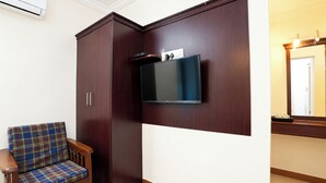 Una habitación con armario, televisor en la pared y una silla de estampado escocés.