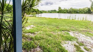 A grassy area with a body of water and trees in the background. - Lakeside Oasis Fort Myers (Fort Myers)