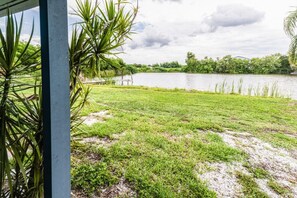 A grassy area with a body of water and trees in the background. - Lakeside Oasis Fort Myers (Fort Myers)