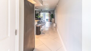 A hallway with a closed door, a trash bin, and a kitchen area with a dining table and chairs. - Lakeside Oasis Fort Myers (Fort Myers)
