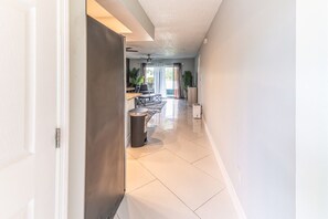 A hallway with a closed door, a trash bin, and a kitchen area with a dining table and chairs. - Lakeside Oasis Fort Myers (Fort Myers)