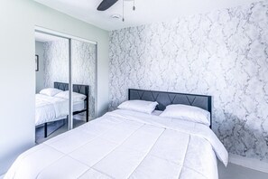 A bedroom with a bed, a wardrobe, and a marble-patterned wall. - Lakeside Oasis Fort Myers (Fort Myers)