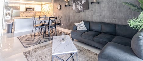 A modern living room with a sofa, coffee table, and dining area with chairs.