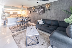 A modern living room with a sofa, coffee table, and dining area with chairs. - Lakeside Oasis Fort Myers (Fort Myers)