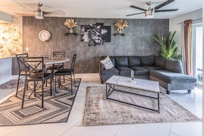 A modern living room with a dining area, grey sofa, and decorative wall art. - Oasis on the Shore of Lake Fort Myers (Fort Myers)