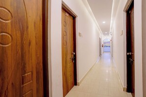 Pasillo de hotel con puertas de madera, piso de baldosas y un letrero que indica un restaurante.