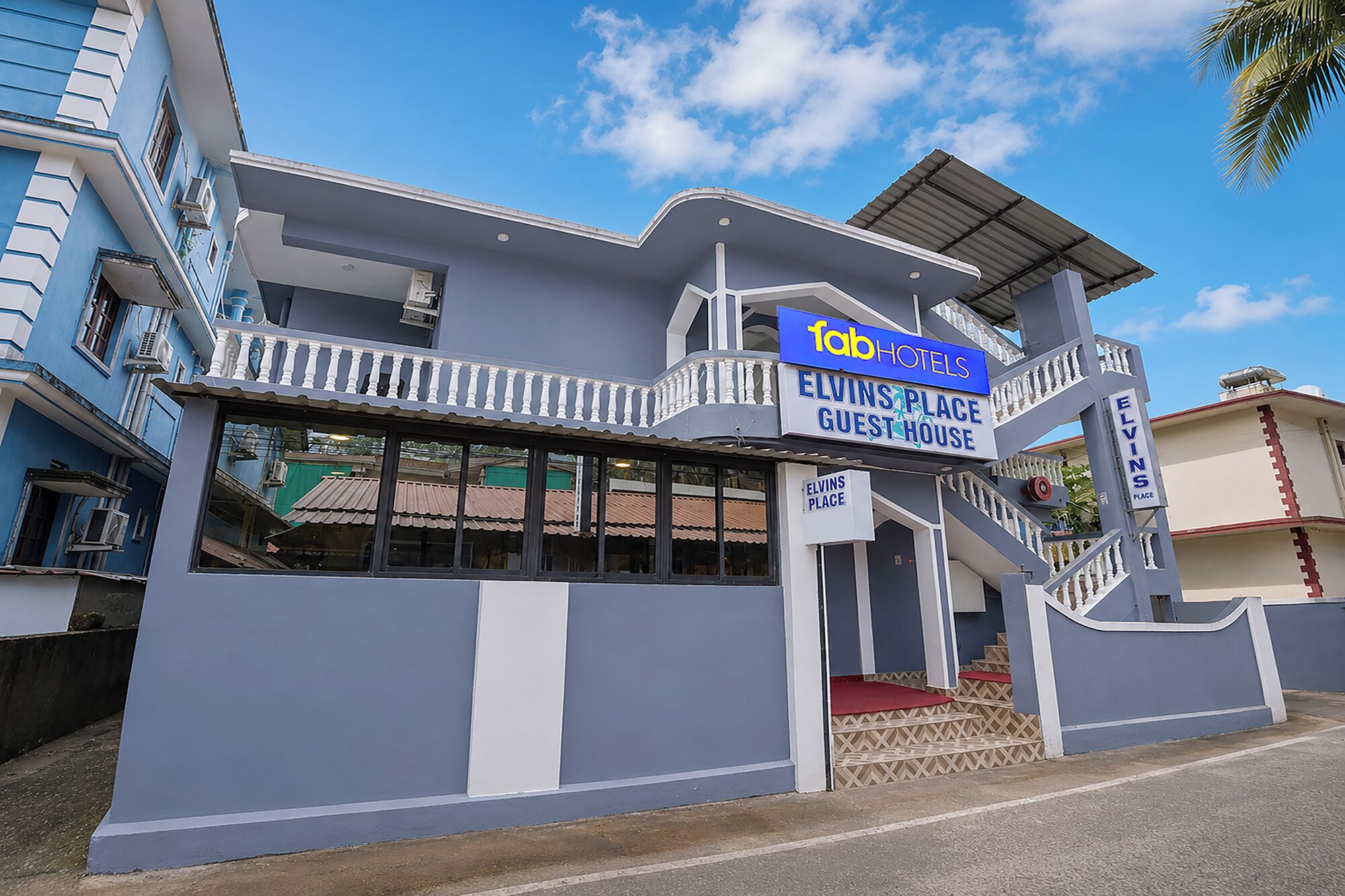 Un edificio de dos pisos con un letrero que dice 'Fab Hotels' y 'Elvin's Place Guest House'.