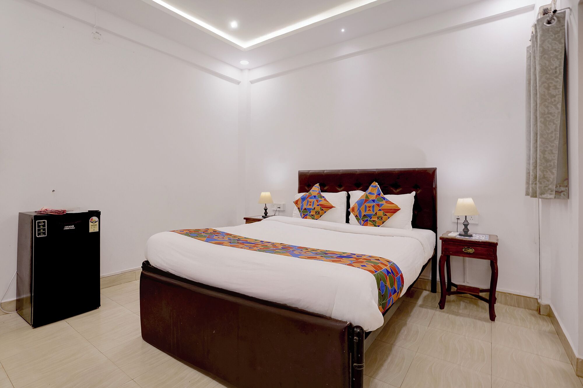 Una habitación de hotel con cama, mesitas de noche, un armario y un escritorio pequeño.