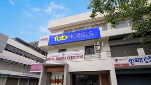 Un hotel con un letrero azul que dice 'fab hotels' y un anuncio para 'hotel dwarka executive' que indica habitaciones de lujo y familiares sin aire acondicionado.