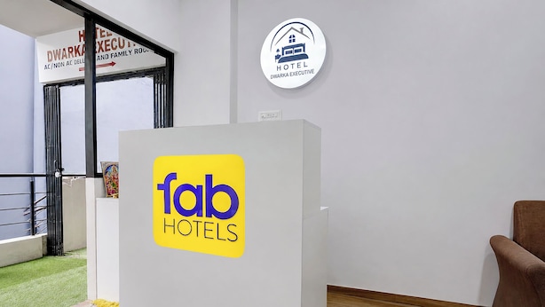 Zona de recepción de hotel con un cartel que dice 'fab hotels' y un logotipo circular para 'DWARKA EXECUTIVE'.