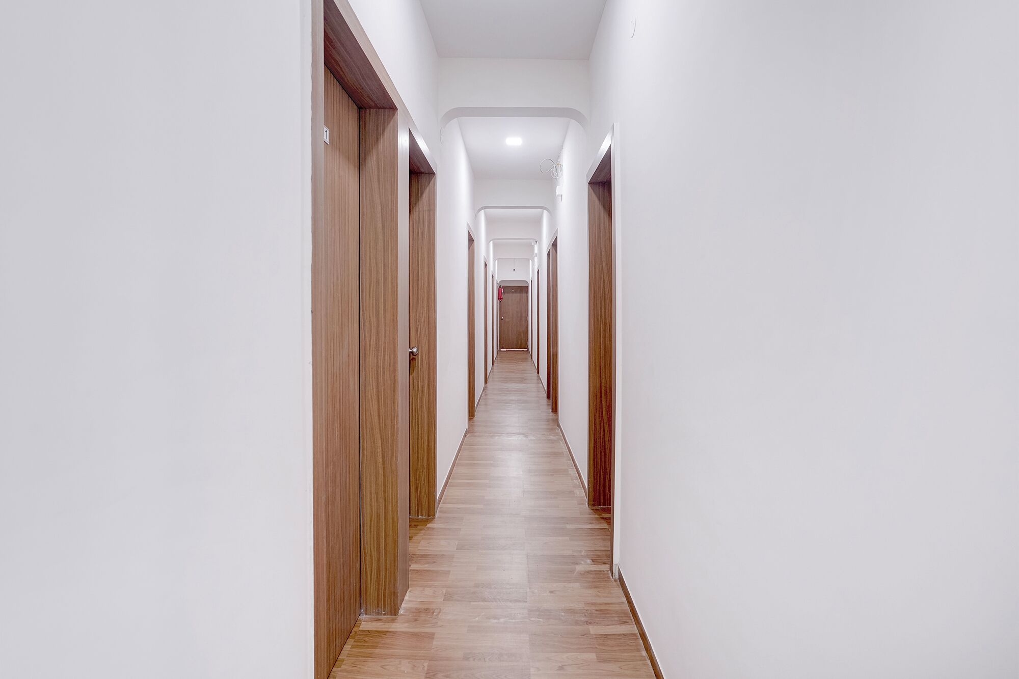 A long, narrow hallway with wooden doors on both sides and a wooden floor.
