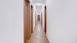 Un pasillo largo y estrecho con puertas de madera a ambos lados y suelo de madera.