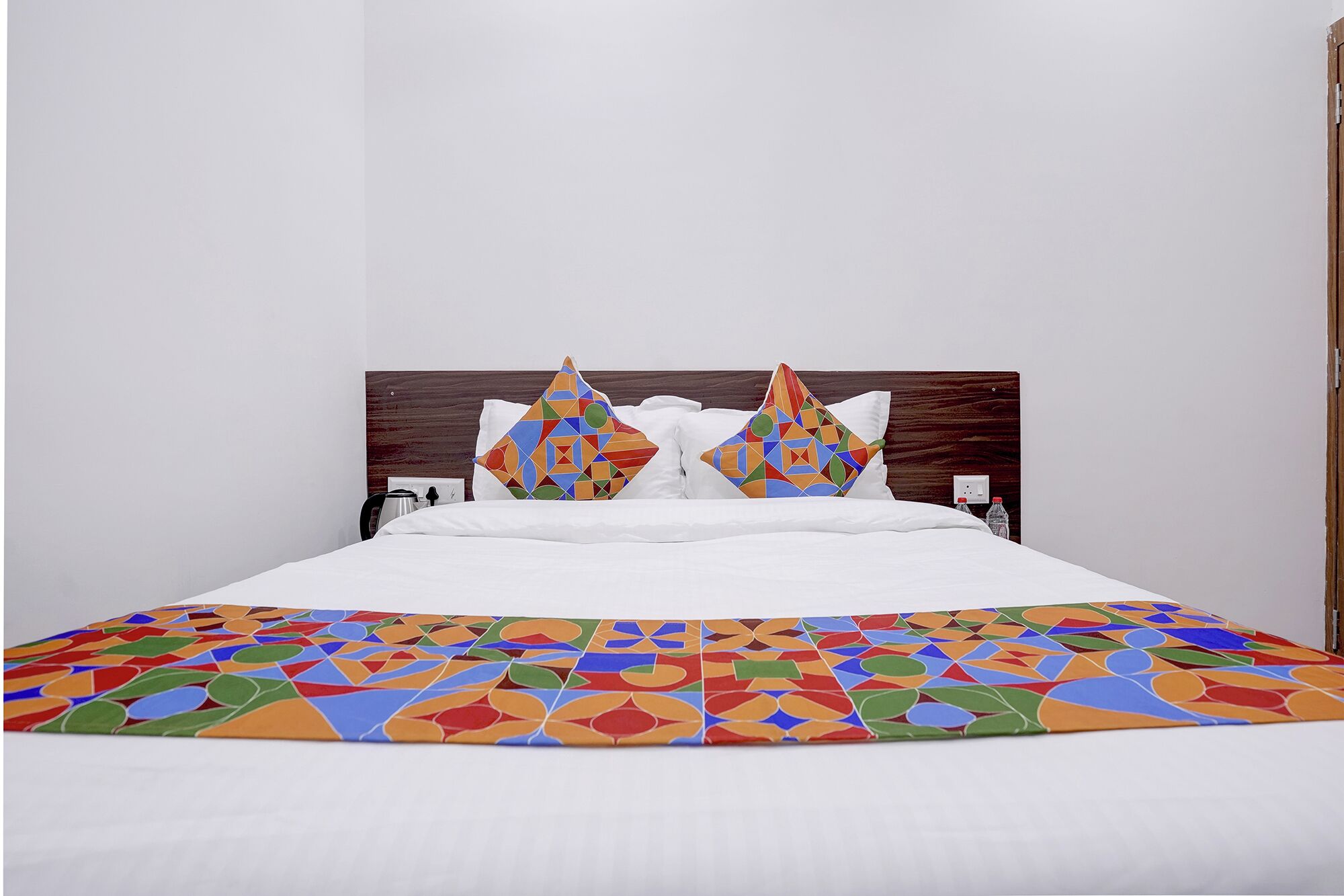 A bed with a geometric-patterned bedspread and two decorative pillows.