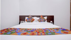 Una cama con un edredón estampado con motivos geométricos y dos almohadones decorativos.
