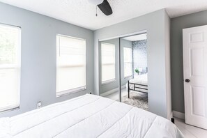 Une chambre avec un grand lit, une porte et une vue sur un balcon, accessible par une porte ouverte.
